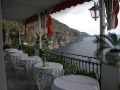 Blick von einer Terrasse mit zahlreichen Sitzgruppen auf Wasser und Felsen - Übernachtung während einer individuellen Wanderung in Italien