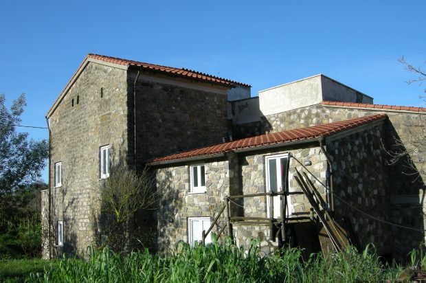 Ein graues steinernes Haus mit rotem Dach und weißen Fenstern - Übernachtung während einer individuellen Wanderung in Italien