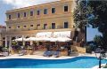 Ein hellgelbes Hotel mit großem Pool und Liegestühlen darum - Übernachtung während einer individuellen Wanderung in Italien