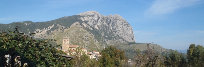 Ein großer Berg vor strahlend blauem Himmel, mit Bäumen im Vordergrund - gesehen auf einer individuellen Wanderung in Süd-Italien