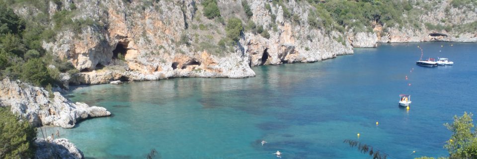 Begrünte Felsen hinter türkisblauem Wasser einer Bucht - gesehen auf einer individuellen Wanderung in Süd-Italien