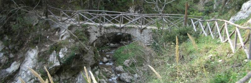 Blick auf eine steinerne Brücke umgeben von zahlreichen Sträuchern - gesehen auf einer individuellen Wanderung in Italien