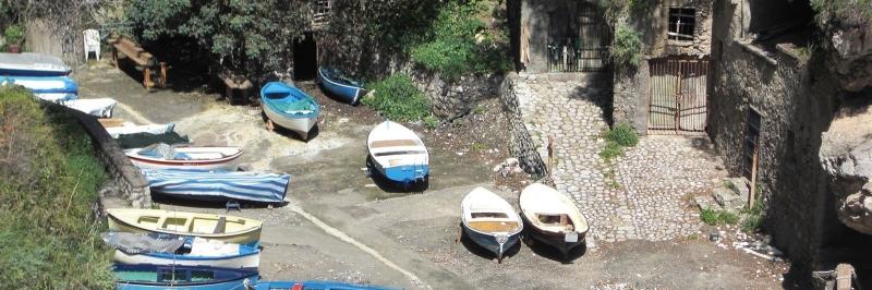 Fünf verschieden kleine Boote auf einem Steinweg - gesehen auf einer individuellen Wanderung in Italien