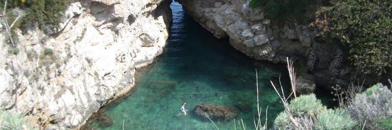 Eine kleine Bucht mit strahlend blauem Wasser umgeben von zwei großen Felsen - gesehen auf einer individuellen Wanderung in Italien